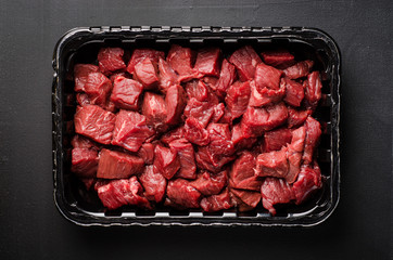 Closeup Raw sliced beef meat in plastic container on dark background. Background with copy space. Selective focus. Top view