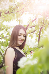 Naklejka premium Portrait of beautiful smiling young woman in flowering spring garden