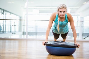 Fit blonde doing push up on bosu ball