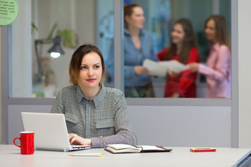 Young female Trainee working on Laptop in Office Interior