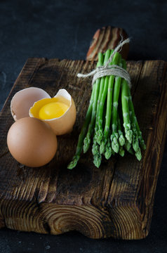 Fresh asparagus with eggs on a wooden cutting board