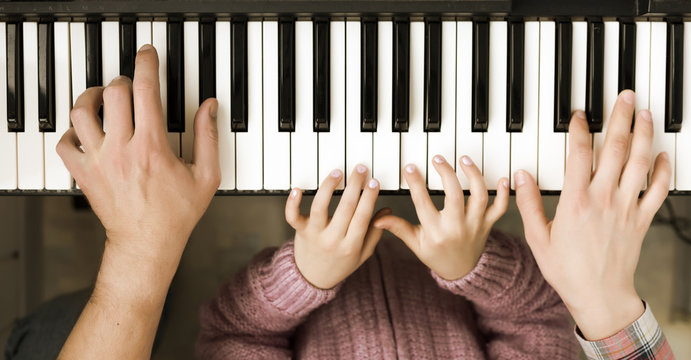 Piano Keyboard top View and Hands of Child Mother and Father