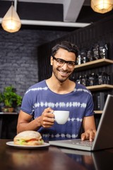 Fototapeta na wymiar Man using a laptop and drinking coffee