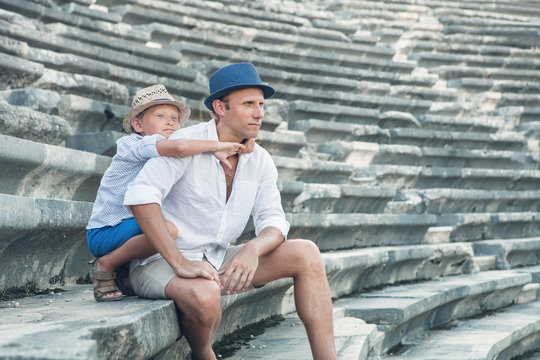 Father with son sitting on antique amfitheater steps