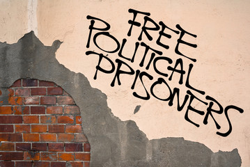 Handwritten graffiti Free Political Prisoners sprayed on the wall, anarchist aesthetics. Appeal to criticize government that persecute their opposition