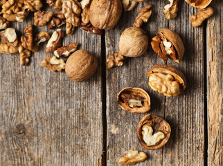Obraz na płótnie Canvas Walnut kernels and whole walnuts on rustic old wooden table