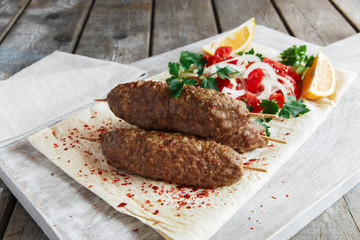 Grilled kebab meat on wooden skewers with vegetables