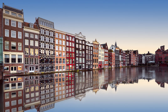 Row of traditional narrow colourful terraced houses reflected in a canal at sunset, Amsterdam, North Holland, Netherlands