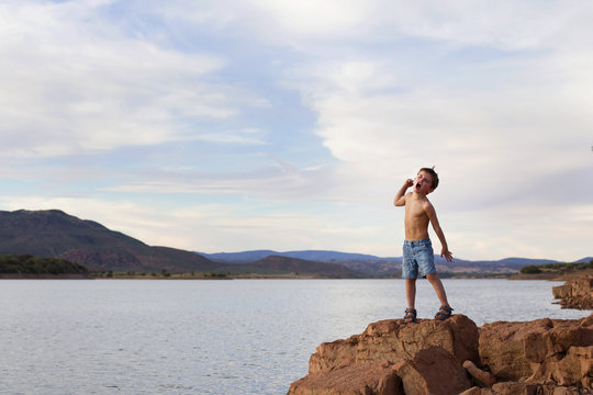 Shirtless Boy standing on a rock on a summer day shouting, Granada, Andalucia, Spain