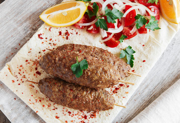 Grilled kebab meat on wooden skewers with vegetables