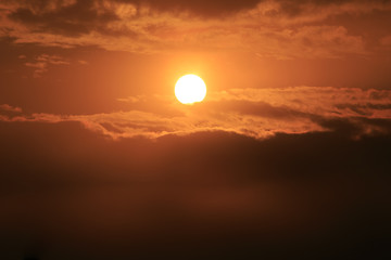 Orange sunset sky with a Sun and feather clouds