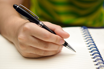 Hand hold a pen and write on a book