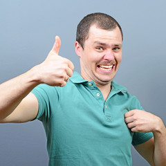 Portrait of a man showing thumb up or ok sign against gray backg