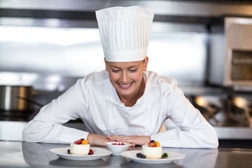 Female chef looking at food plates in kitchen