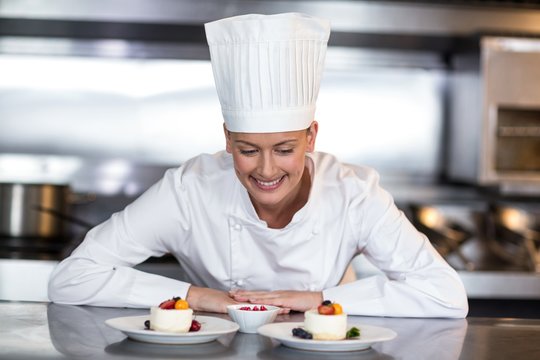 Female Chef Looking At Food Plates In Kitchen