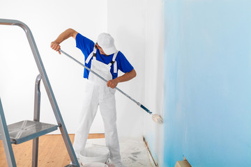 Painter painting a wall with paint roller © guerrieroale