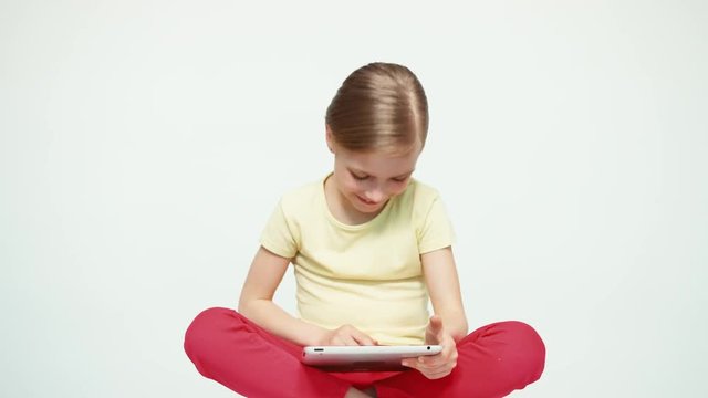 Girl 7-8 years old using tablet pc sitting on the white background