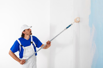 Painter painting a wall with paint roller © guerrieroale