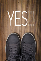 Sneakers with Yes!!! written on wooden floor