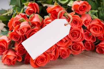 Bouquet of pink red roses and greeting card on a wooden background