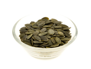 pumpkin seeds  in a glass bowl. Isolated on white.
