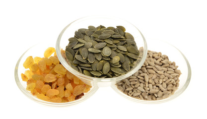 pumpkin seeds,sunflower seed, raisins in a glass bowl. Isolated on white.
