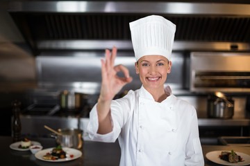 Portrait of smiling female chef showing ok sign - Powered by Adobe