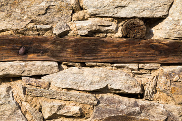 Old natural stone or rock wall with wooden beam