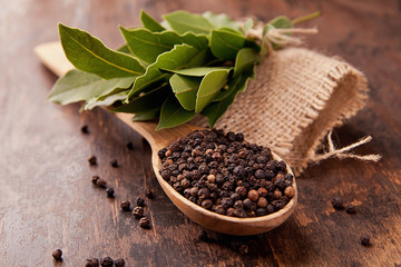 pepper in wooden spoon with garlic, bay leaves
