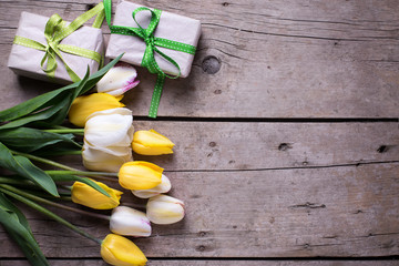 Bright yellow and white spring tulips and box with presents on a