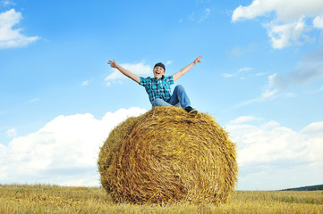 Naklejka na ściany i meble man on a stack of straw against a field