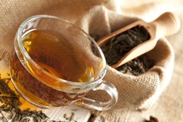 Cup of tea and tea leaves on wooden table