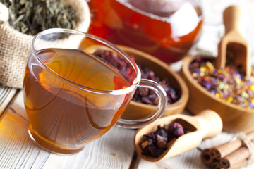 Cup of tea, teapot and mix of assorted tea leaves on wooden tabl