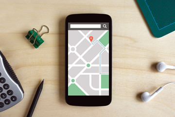 Map gps navigation application on smart phone screen on wooden desk. All screen content is designed...