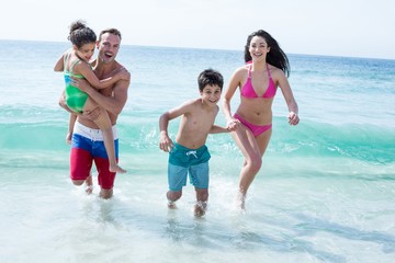 Father and mother running with children at beach 