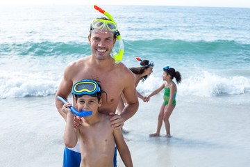 Family wearing diving goggles standing at beach 