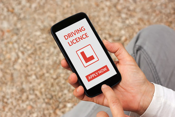 Hands holding smart phone with driving licence app mock up on screen. All screen content is...