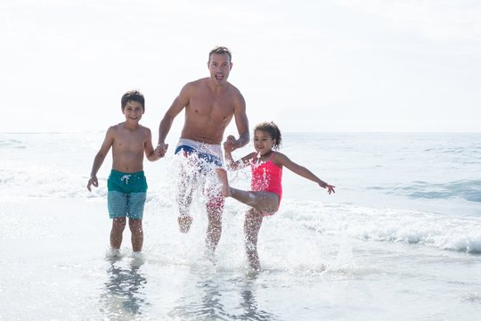 Cheerful father enjoying with children in shallow water