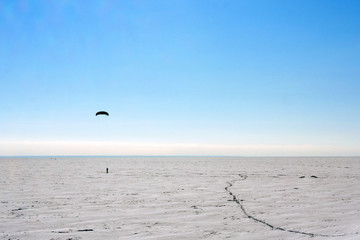 Silhouette of a man kiting in winter time at frozen lake