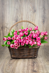 Tulips in the wicker on wooden background