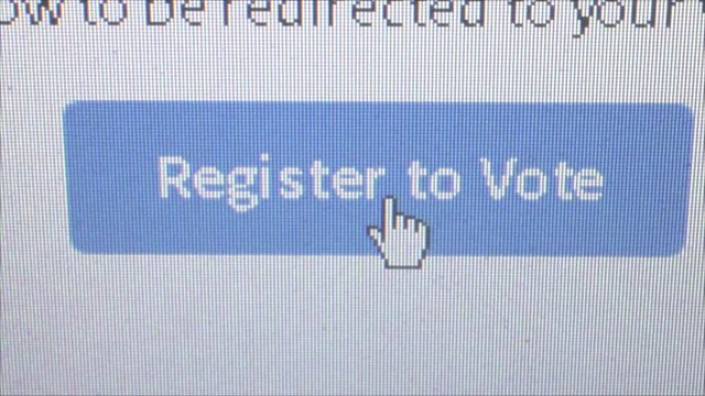 Macro close up dolly into live computer monitor showing a banner which says 'register to vote', shot at pixel level with special lenses. User then moves cursor and clicks on banner
