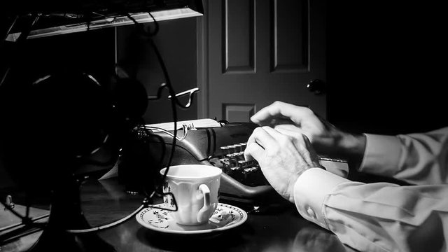 Dimly lit Film Noir setting of a man typing on a 1940 manual typewriter with an old electric fan and classic teacup and saucer close by.