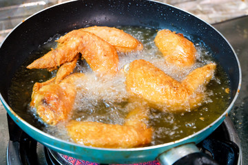 Fried chicken wings in frying pan 