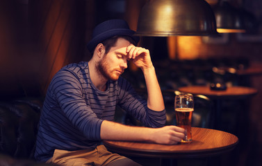 unhappy lonely man drinking beer at bar or pub