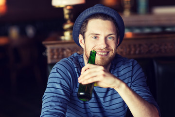 happy young man drinking beer at bar or pub