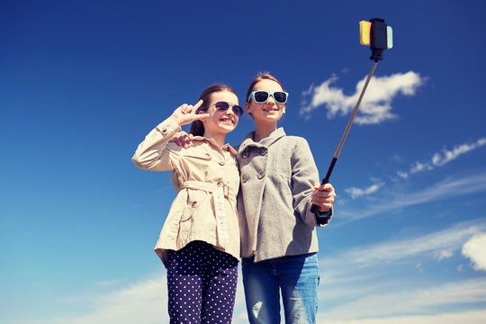 happy girls with smartphone selfie stick