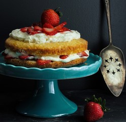 Strawberry shortcake on beautiful cake stand on dark moody background
