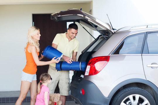 happy family packing things to car at home parking