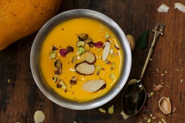 Mango pudding with nuts and cream served in a metal serving dish