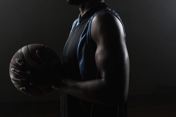 Zoom on a side of  a basketball player holding a basketball